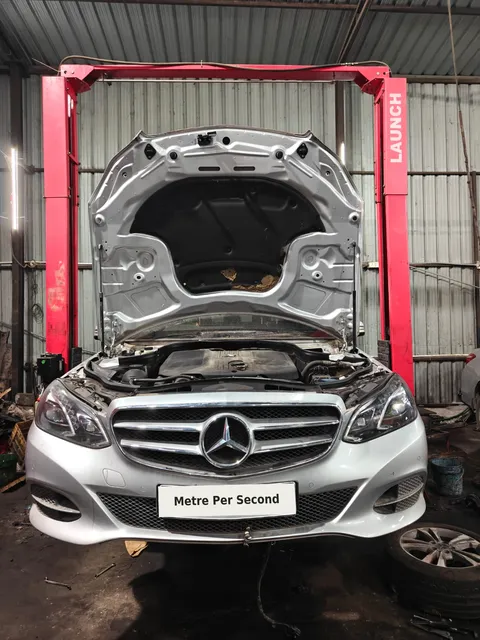 Silver Mercedes-Benz E-Class with bonnet open on a workshop lift